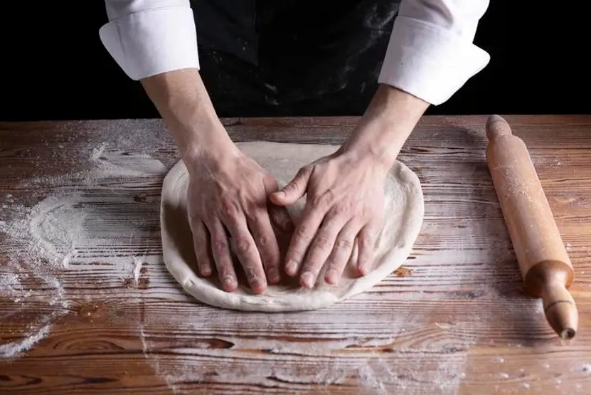 Hands stretching a perfect pizza dough.