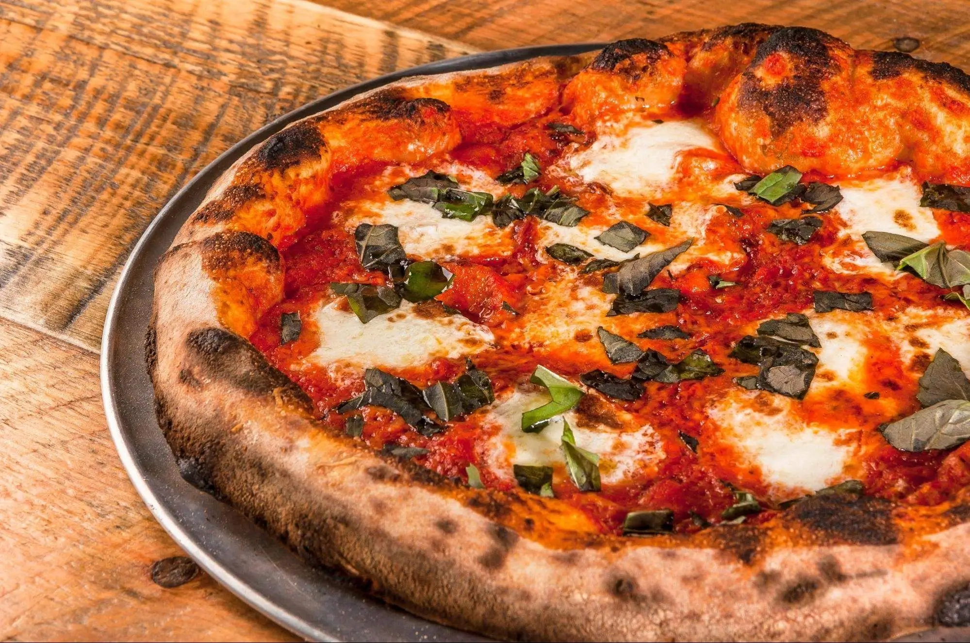 A close-up of the leopard-spotted charred crust of a Neapolitan pizza.