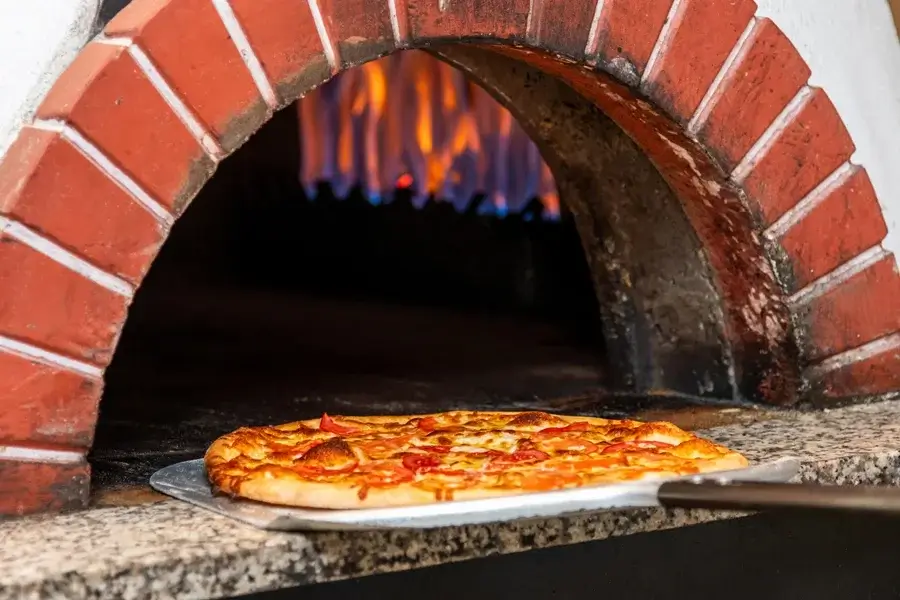 Roaring flames inside a brick pizza oven.