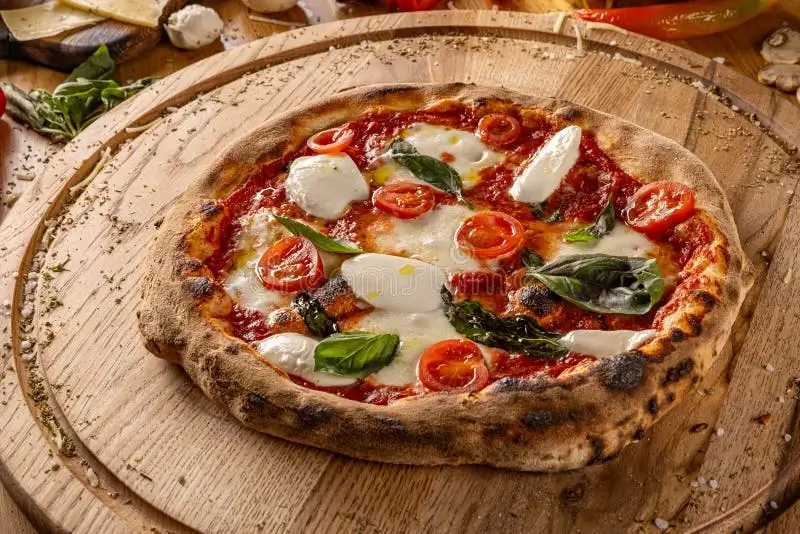 Fresh basil, tomatoes, and mozzarella arranged on a rustic table.